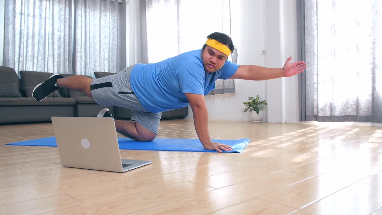 Fat Man Does Yoga At Home While Looking At His Laptop
