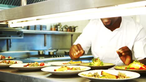 chef garnishing meal at order station of commercial kitchen