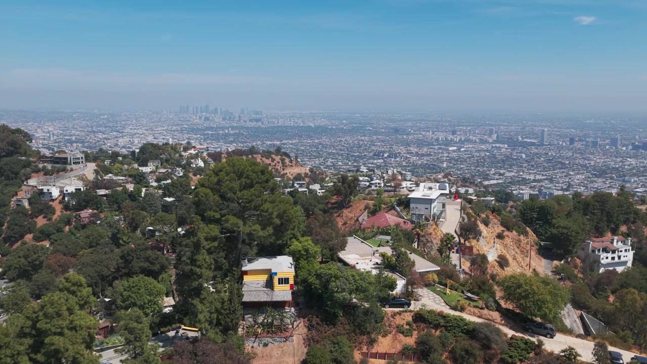Inquadratura aerea con teleobiettivo in panning di case in cima alle montagne sopra Los Angeles, California. 4K.