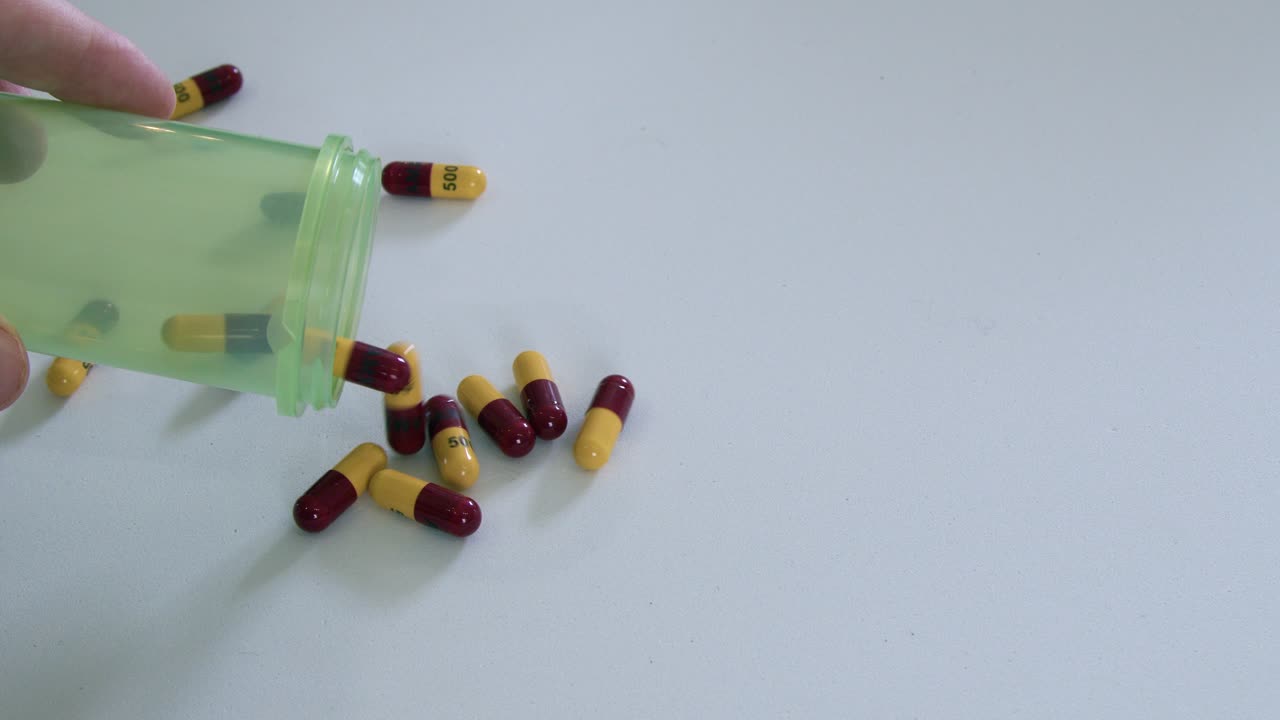 Yellow and red capsule amoxicillin antibiotic pills poured onto table