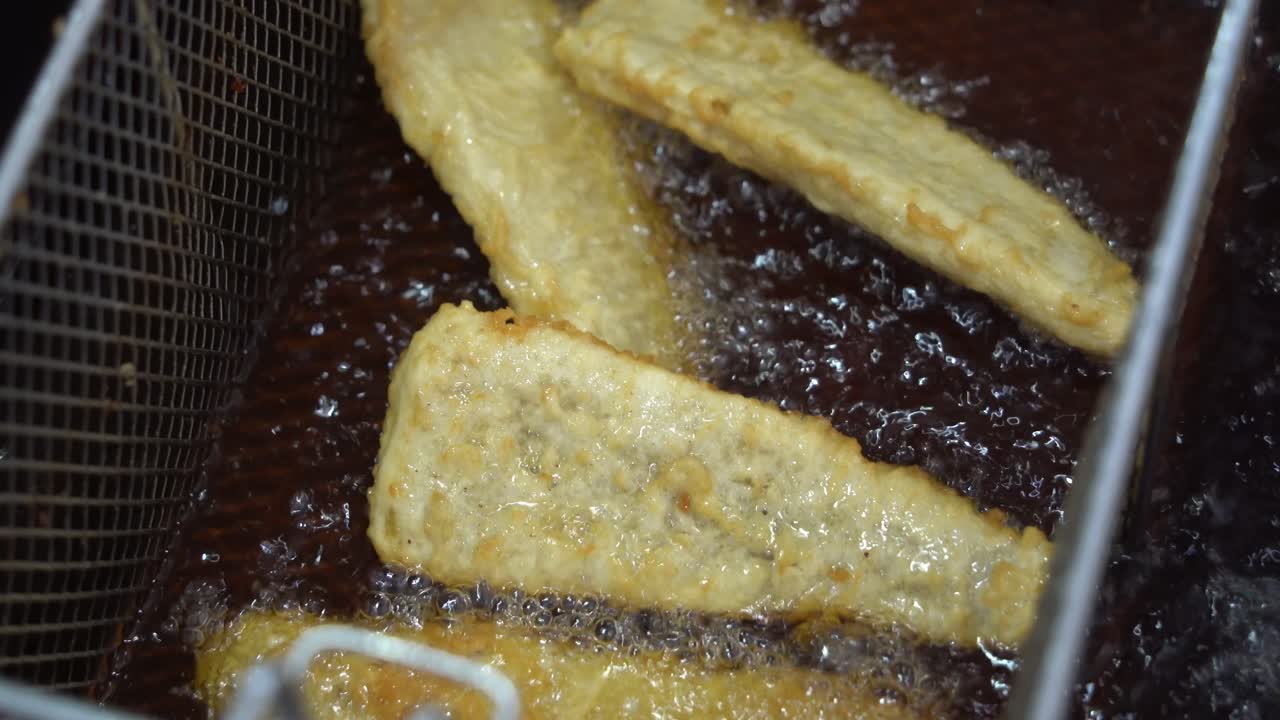 황금빛 맛있는 바삭한 생선 필레, 진행 중인 전통 피쉬 앤 칩스 요리, 끓는 뜨거운 기름 패스트 푸드 상업용 주방, 야시장 펍 음식, 클로즈업 샷