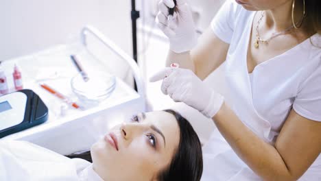 an experienced tattooist checks the work of the machine for permanent make-up in the presence of the client in the cosmetology before the procedure. close-up.