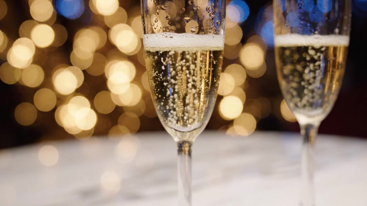 Brindisi celebrativo: champagne frizzante in eleganti flûte su uno sfondo scintillante di luci festive, catturando l'essenza di momenti gioiosi e occasioni speciali