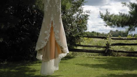 precioso vestido de novia de diseñador ondeando al viento mientras cuelga de un árbol en una superficie cultivada en el centro de eventos y bodas strathmere en ottawa, canadá