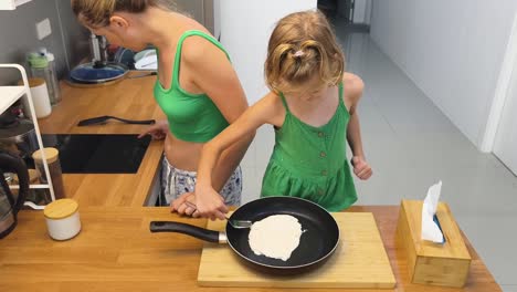 mother and daughter cooking pancakes together