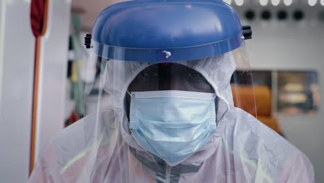 african american paramedic in hazmat suit looking at camera weary black male medical practitioner in hazmat suit with mask and face shield looking at camera while riding ambulance to emergency during pandemic
