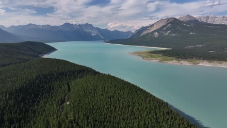 The-blue-green-glacial-waters-of-Abraham-Lake-as-seen-from-a-drone-as-it-flies-across-the-forest-of-the-Rocky-Mountains-of-Alberta,-Canada