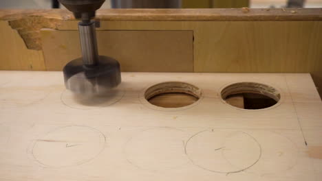 close-up clip of a drill press in the process of drilling a hole in a small sheet of plywood