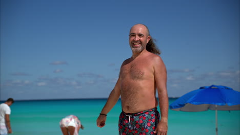 cámara lenta de un feliz hipster mexicano alternativo con los brazos abiertos como una invitación sonriendo y riendo en una playa en cancún, méxico