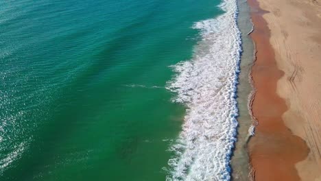 Toma-Aérea-De-Largas-Olas-Rompiendo-En-Una-Playa-De-Arena-Vacía