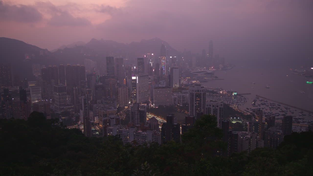 tomada panorámica del horizonte de la ciudad de hong kong con rascacielos y vista del puerto al anochecer desde un ángulo alto