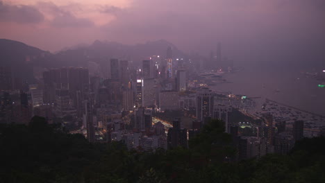 pan shot of hong kong city skyline with skyscrapers and harbour view at dusk hour from high angle