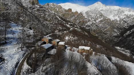 antena: ciudad de montaña nevada en la ladera de una montaña en los pirineos catalanes con altas montañas nevadas en el fondo