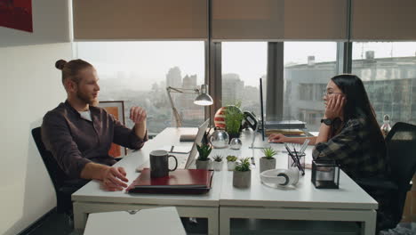 Two-people-communicating-city-view-office-close-up.-Relaxed-developers-talking