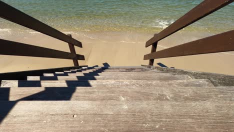 Plano-Ajustado-De-Mirar-Hacia-Abajo-Los-Escalones-A-Aguas-Poco-Profundas-Y-Una-Playa-De-Arena-Limpia