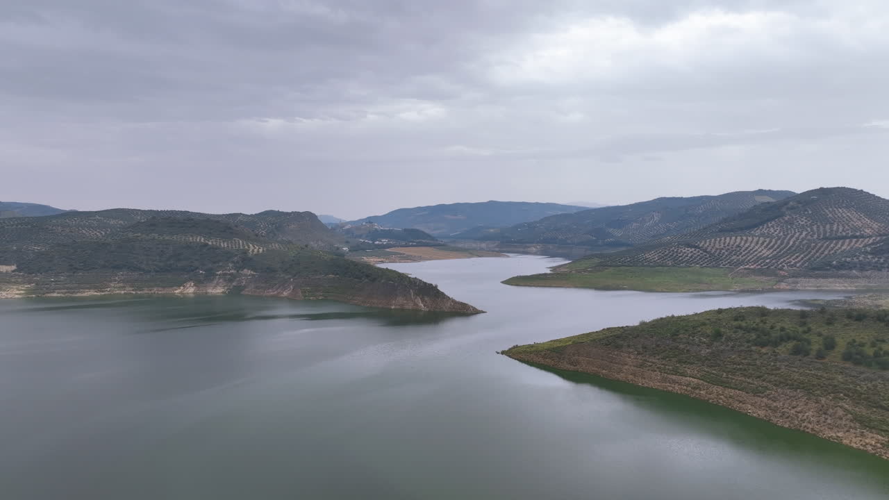 Slow glide high above gloomy atmospheric waters of Spain's giant Lake Iznajar
