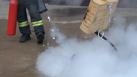 bombero irreconocible usando un extintor de incendios para extinguir la cuerda en llamas