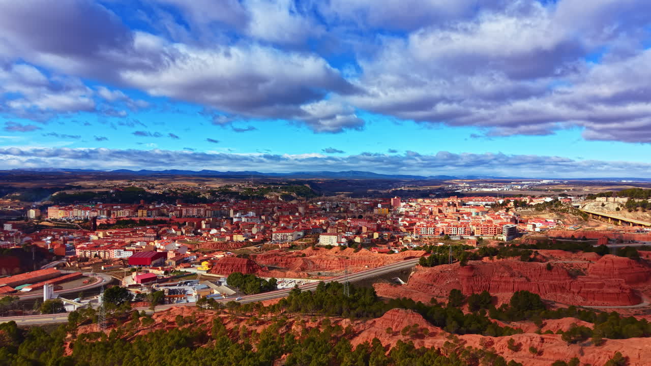 Vista de un pueblo rodeado de colinas rojas y cielo azul claro tomada durante el día en el campo