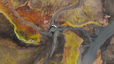 Aerial-view-directly-above-dramatic-Iceland-landscape,-transport-van-parked-on-remote-road