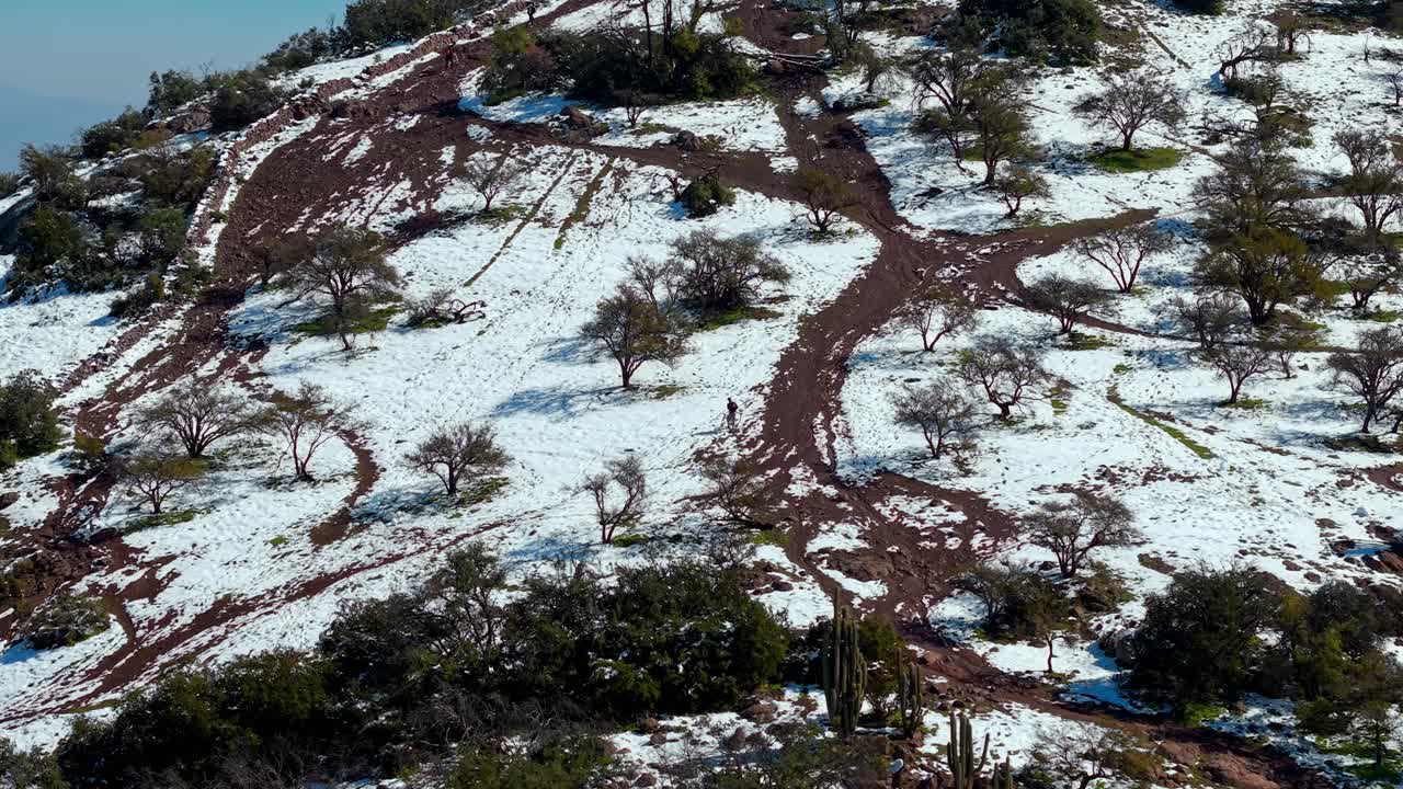 Bird’s-eye view of a cyclist riding the snowy slopes of Manquehuito hill near Santiago