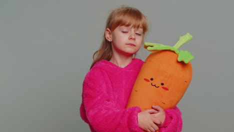 a young girl holding a plush carrot toy and smiling