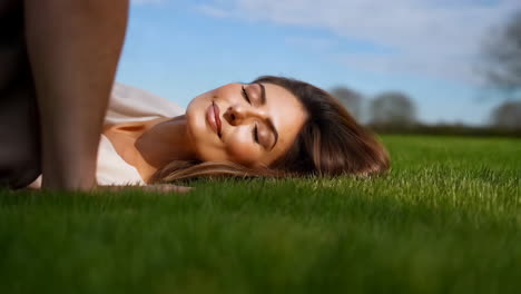woman relaxing on green grass in sunlight