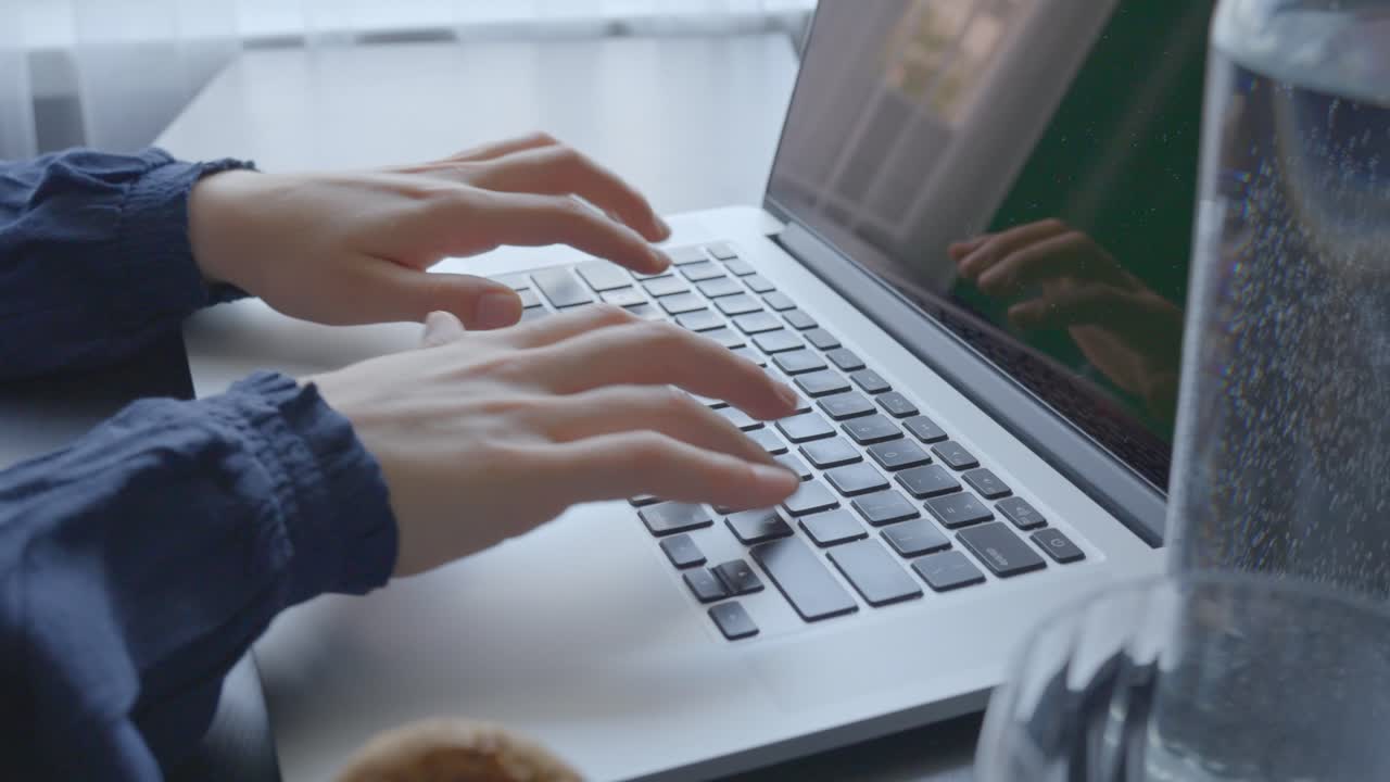 Hands of woman typing on laptop keyboard, close up motion view