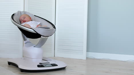 sweet newborn baby girl sleeping in a bouncer chair in a white room