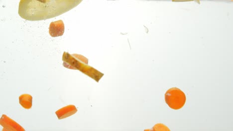 mixture of freshly chopped fruits dropped into water, white background