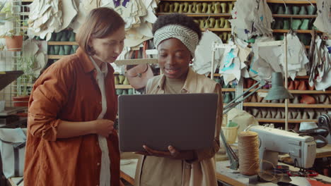 Colegas-Femeninas-Usando-Laptop-Y-Hablando-En-Taller-De-Zapatería