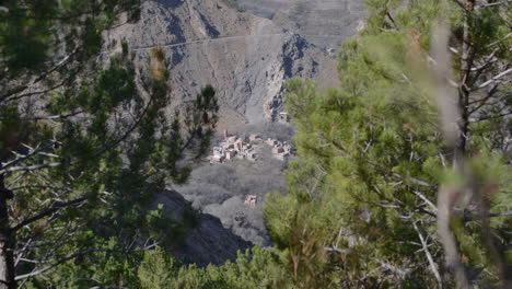 Un-Pueblo-De-Montaña-En-Las-Montañas-Rocosas-Del-Alto-Atlas-De-Marruecos-Enmarcado-Entre-Dos-árboles-Fuera-De-Foco