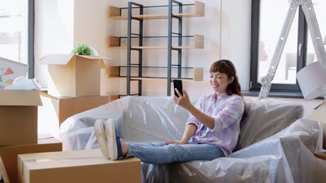 Woman-with-Phone-Having-Video-Call-at-New-Home.moving,-people-and-real-estate-concept--happy-smiling-asian-woman-with-smartphone-and-boxes-having-video-call-at-new-home