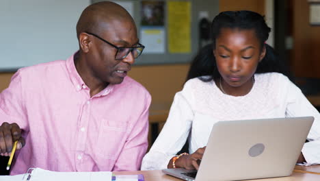 Tutor-De-Secundaria-Dando-A-Una-Estudiante-Usando-Una-Computadora-Portátil-Clases-Uno-A-Uno-En-El-Escritorio