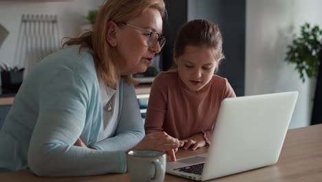 Abuela-Y-Nieta-Caucásicas-Usando-Una-Computadora-Portátil-En-La-Cocina