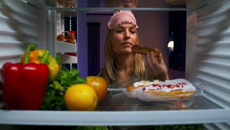 mujer comiendo un bocadillo tarde en la noche en el refrigerador