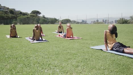 focused diverse elementary school schoolgirls practicing yoga at stadium in slow motion