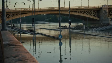 flooded road under a bridge with submerged traffic signs and debris during budapest flood 2024