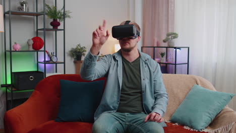 hombre adulto usa gafas de realidad virtual en casa juega videojuegos en 3d haciendo gestos con las manos