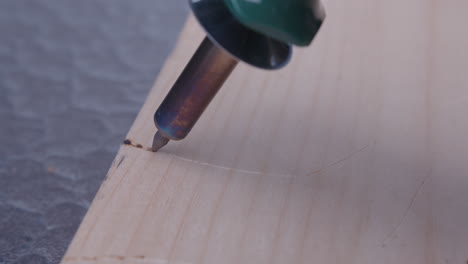 cerca de un lápiz de leña que quema madera escribiendo en un tablón de madera