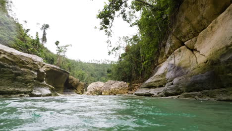 floating downstream in river before diving down below surface in end of clip - slow motion and rainy weather in philippine wilderness