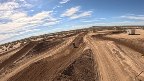 motorcyclist takes a big jump on a dirt racetrack - first-person view drone