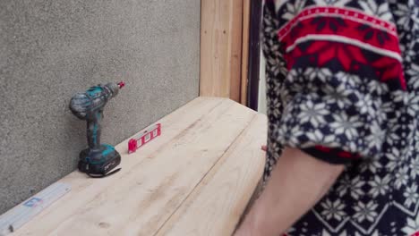 hombre arreglando la tabla de madera para el estante del invernadero
