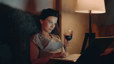 Chica-Navegando-Por-Internet-En-Un-Cuaderno-En-El-Sofá.-Mujer-Bebiendo-Vino-Tinto-Con-Una-Computadora-Portátil.