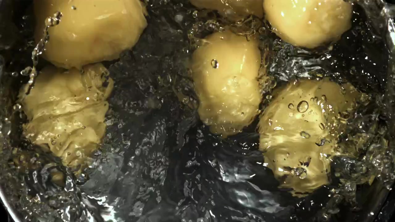 皮をむいたジャガイモがスローモーションで沸騰したお湯に落ちる