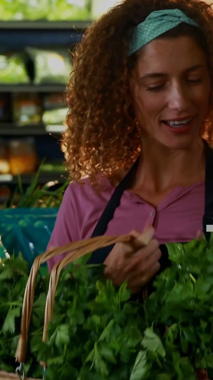 Video verticale: Donna del reparto ortofrutta che annusa erbe aromatiche, con un collega che mostra grafici sulla freschezza per una promozione