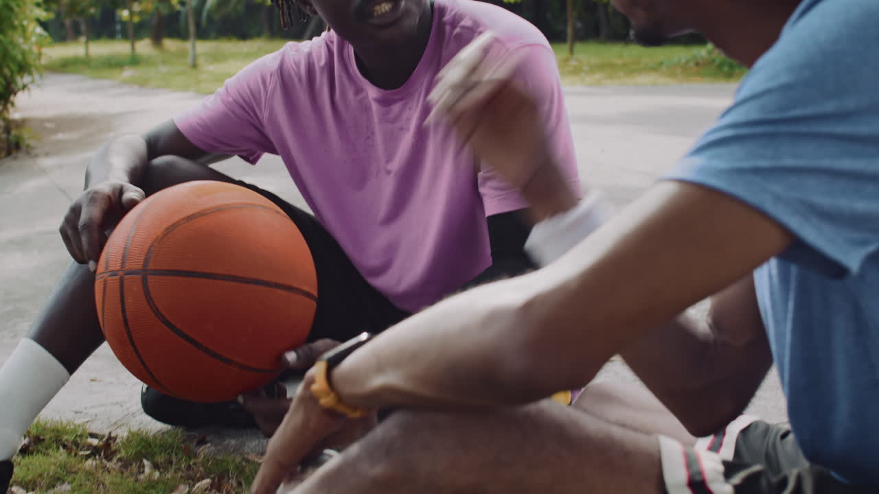 Basketball Players Sitting on Outdoor Court after Game