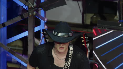 man in black cowboy hat plays red sg guitar on outdoor stage at night