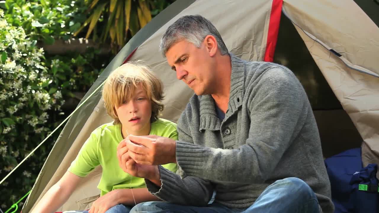 padre mostrando a su hijo cómo preparar aparejos de pesca