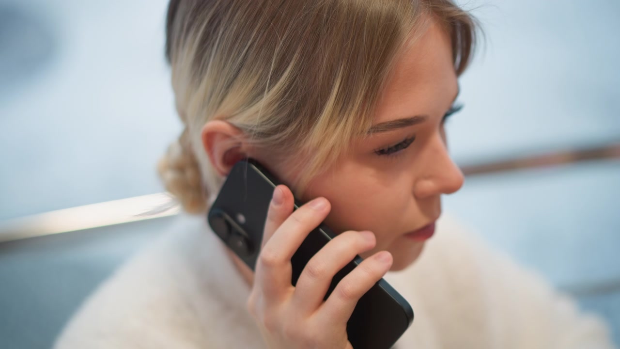 Konuşurken Akıllı Telefonu Kulağına Tutan, Dikkatli İfadeli, Eli Yanağında, Hafif Başı Eğik ve Arkasında Yumuşak İç Mekan Arka Plan Bulanıklığı Olan Yetişkin Bir Kadının Profil Portresi