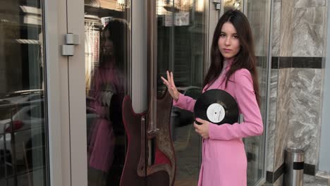 Hermosa-Chica-De-Rosa-Cerca-De-La-Tienda-De-Música-Con-Un-Disco